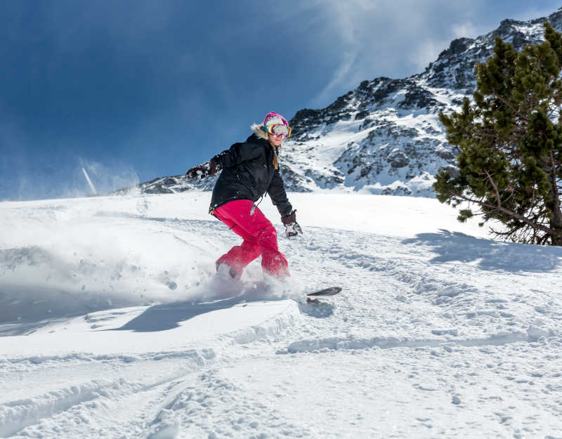在运动的年轻女子滑雪板滑雪板在山