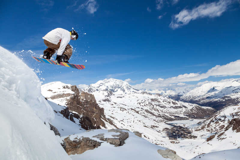 跳跃滑雪板保持一方面对蓝色天空背景的滑雪板
