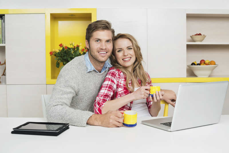 年轻夫妇坐在餐桌前玩电脑