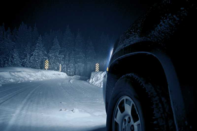 冬季暴风雪中的危险道路上行驶的汽车