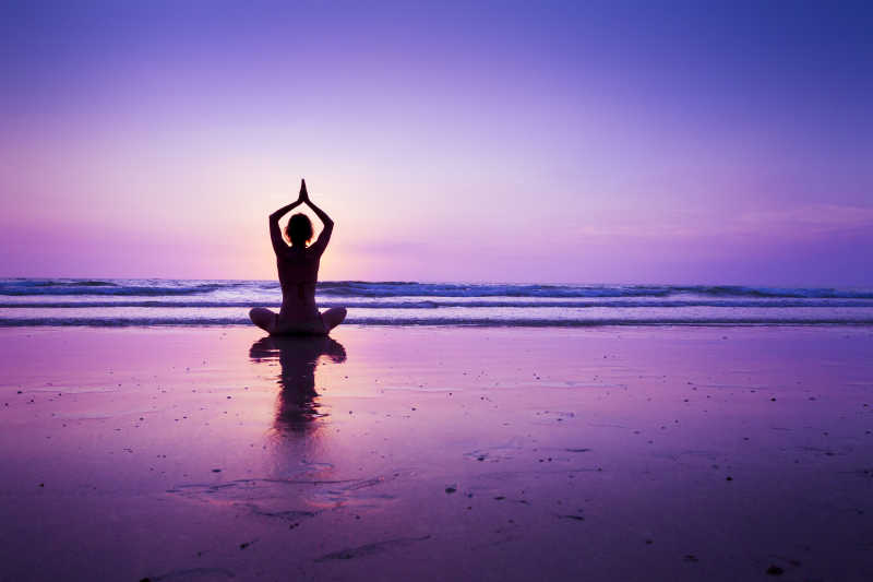 日落海滩上练习瑜伽的女子