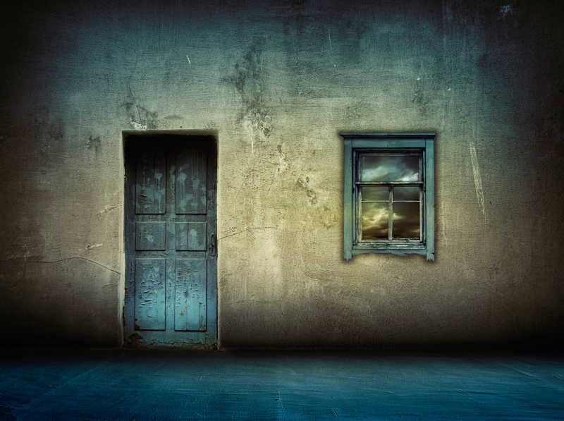 黑暗的老式房屋与蓝色的窗户和木门
