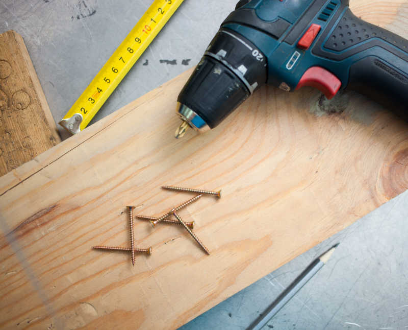 灰色背景下木板上的DIY工具电钻