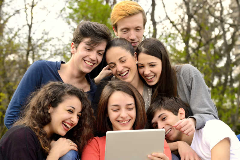 一群年轻人在外面浏览平板电脑