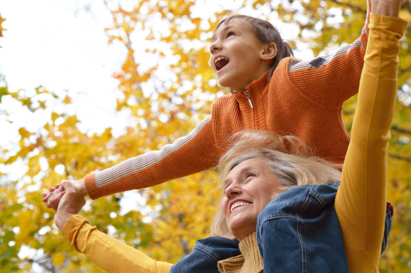 奶奶和她的孩子在秋天的公园里玩