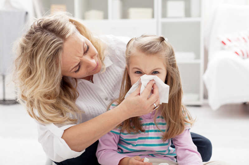 母亲帮生病的小女孩清理鼻子