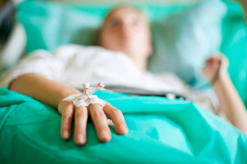 在医院生病的女病人躺在病床上正在输液的手