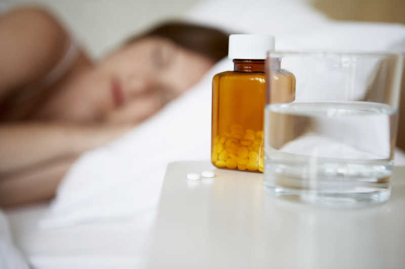 生病的女人睡在床上桌上放着药物和水