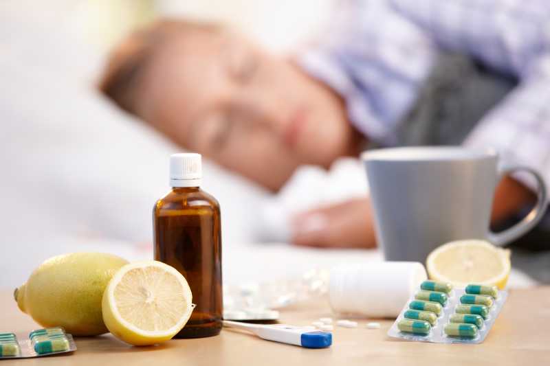 生病睡觉的女病人桌上放着药物体温计和柠檬