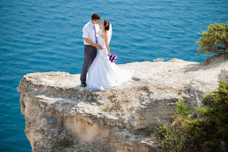 新婚的夫妇在海边悬崖上的婚纱照