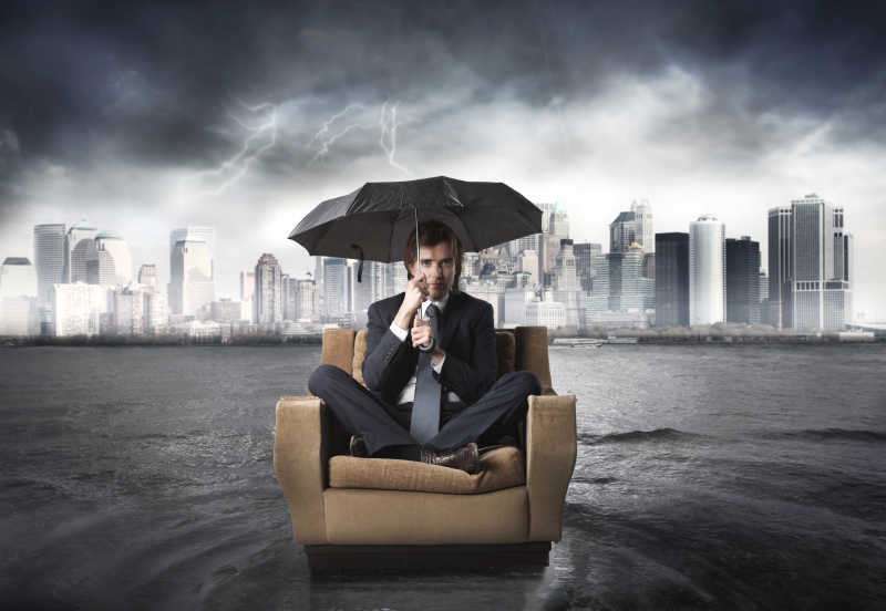 城市雷雨天背景下坐在沙发上打着伞的男人