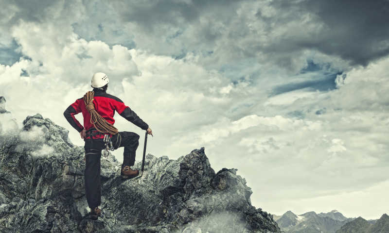 站在峰顶背着登山套索的攀登者眺望云海