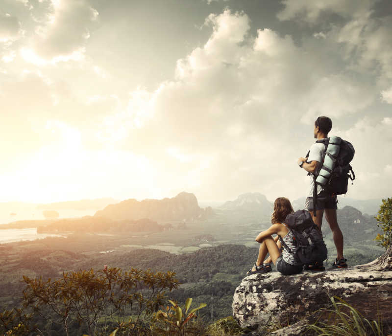 背着双肩包的徒步旅行者从山顶欣赏山谷日出景色