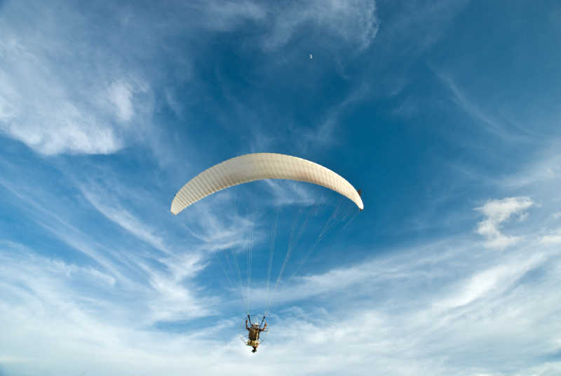 白色的动力伞飞行在蓝色的天空下