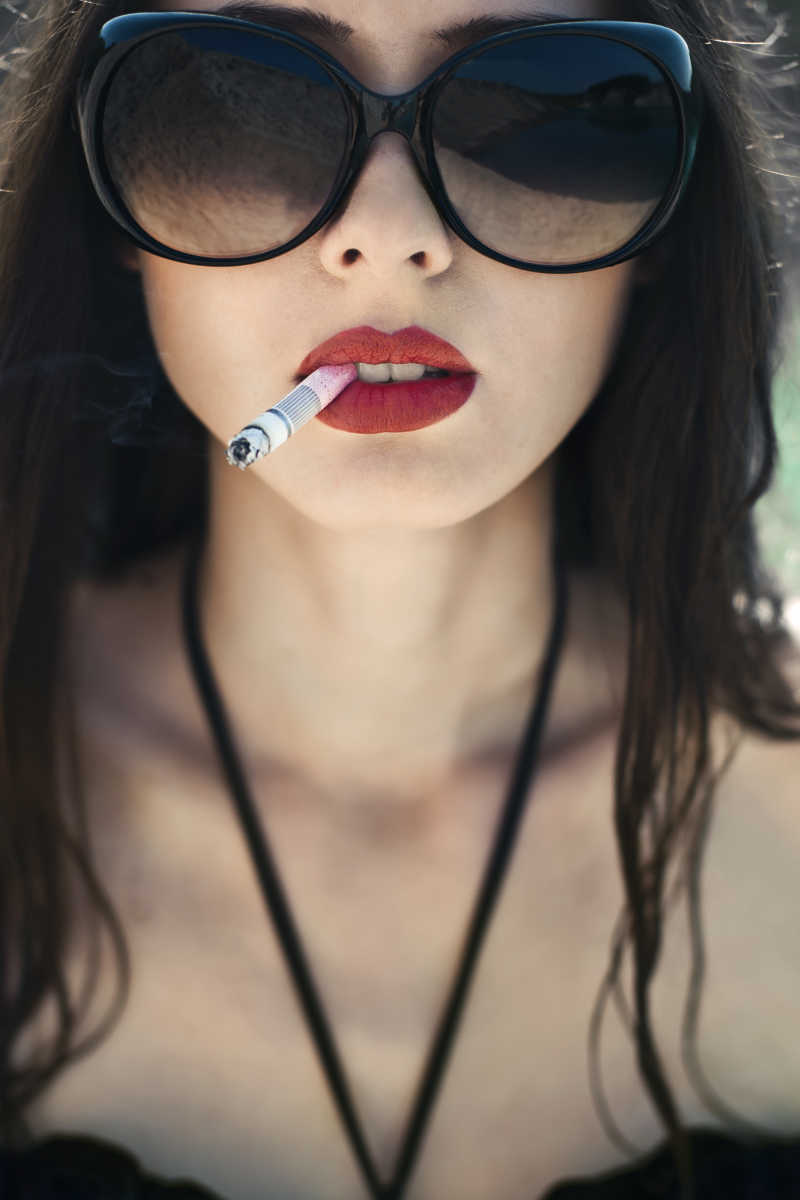 戴眼镜的吸烟的美丽年轻女子