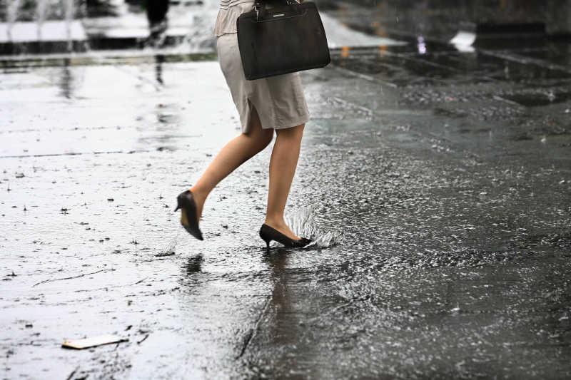 下雨时穿着高跟鞋的女人在路上行走