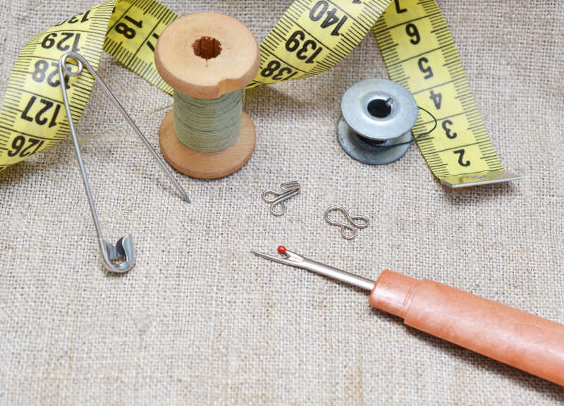 亚麻色布料上的针线皮尺等缝纫工具