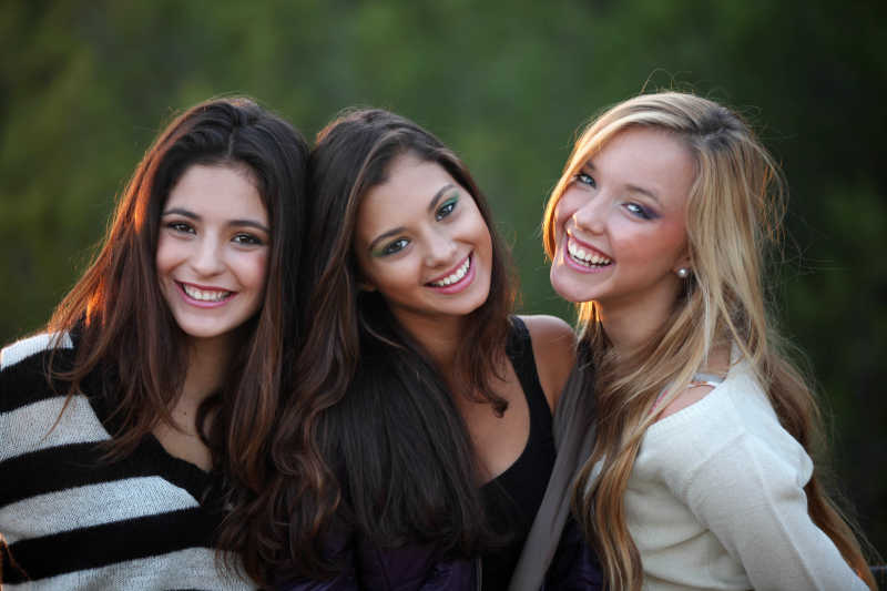 室外绿色背景下的三位微笑的美女