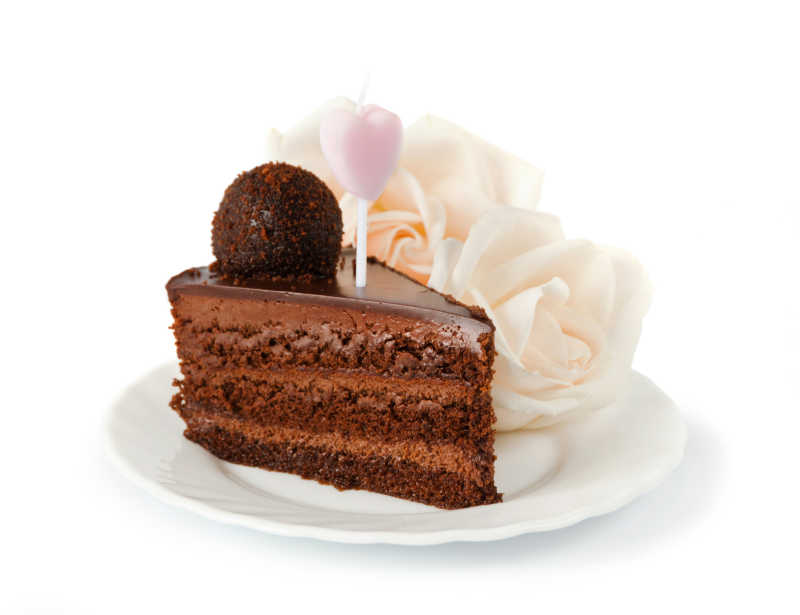 白色瓷盘里一块巧克力蛋糕和两只玫瑰蜡烛