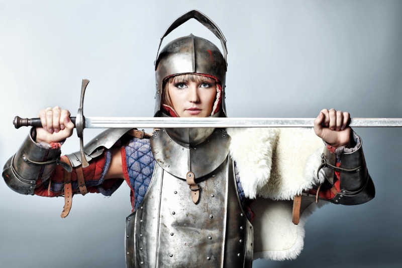 身穿灰色背景穿盔甲女骑士拿着剑肖像