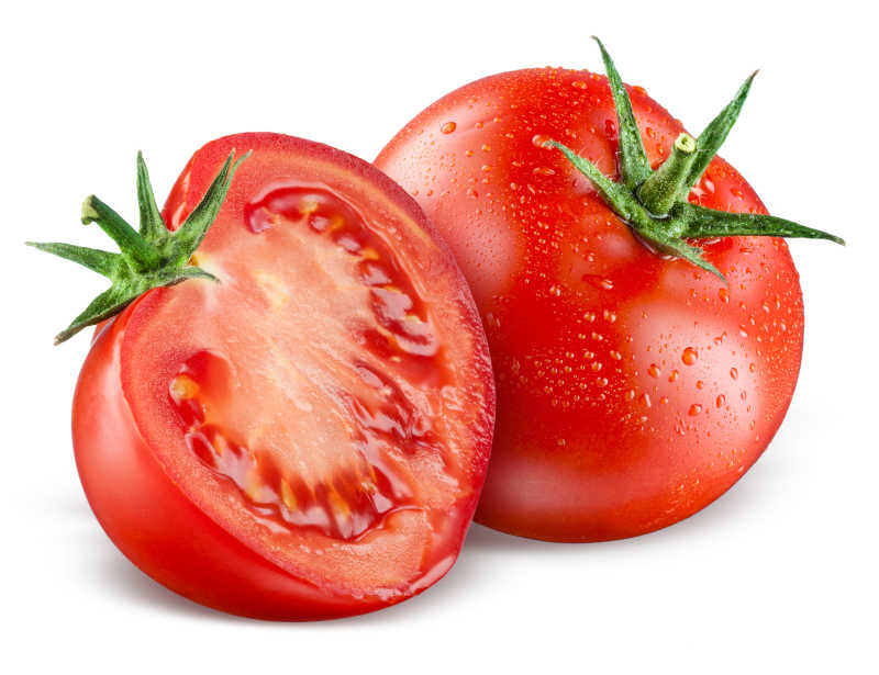 白色背景下滴着水珠的一整个西红柿和切成一半的西红柿