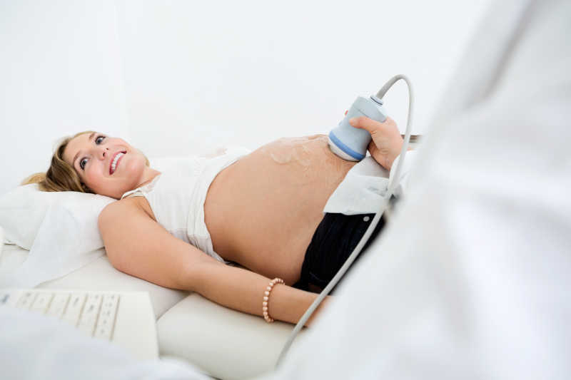 孕妇接受医生使用超声波仪器探查