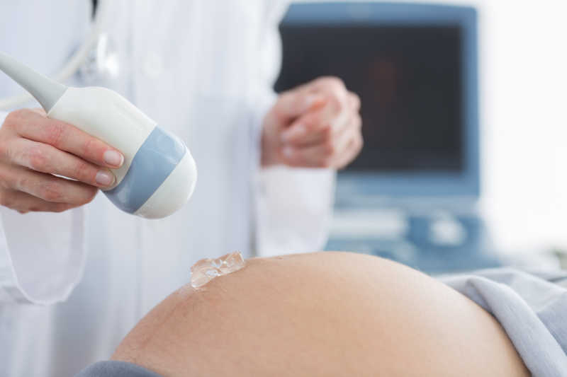 医生用应用凝胶对孕妇腹部进行检查