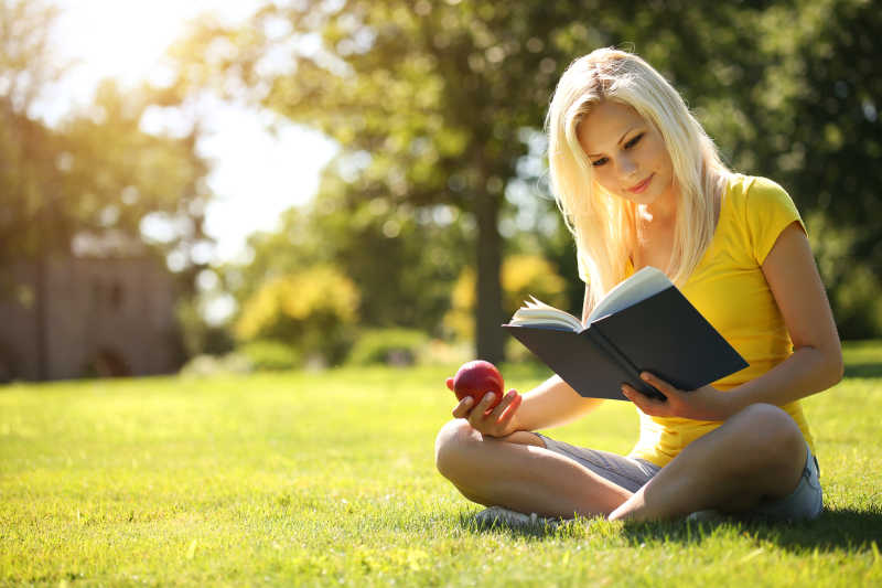 金发的女孩在草地上看书