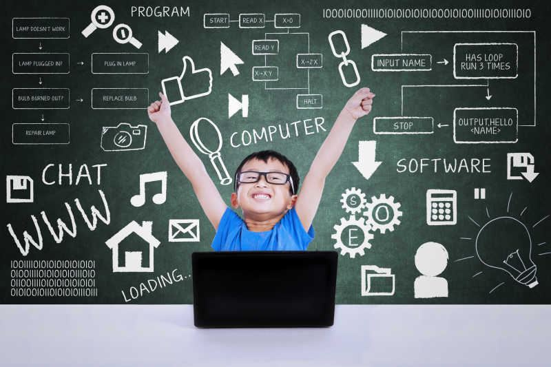 在教室里用计算机快乐学习的小男孩