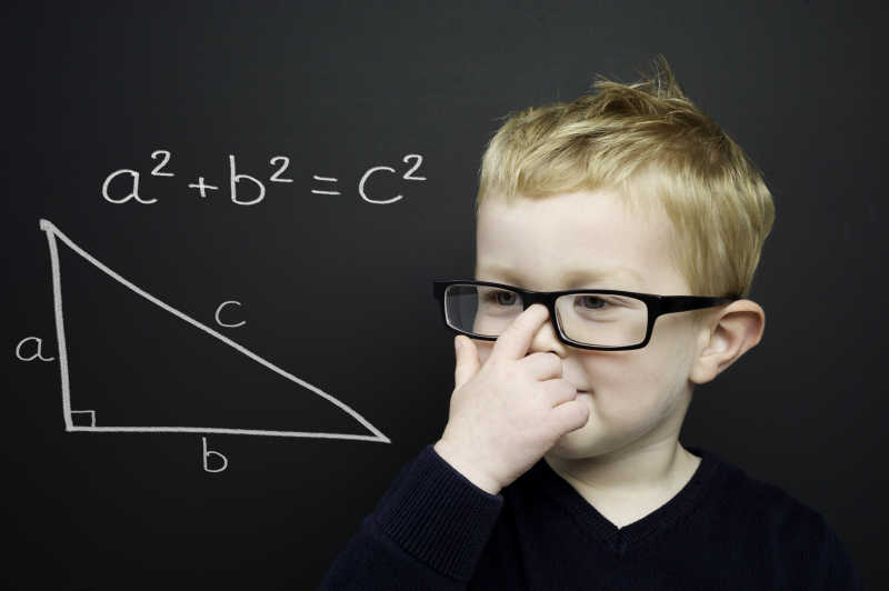 在黑板前思考数学题的小男孩