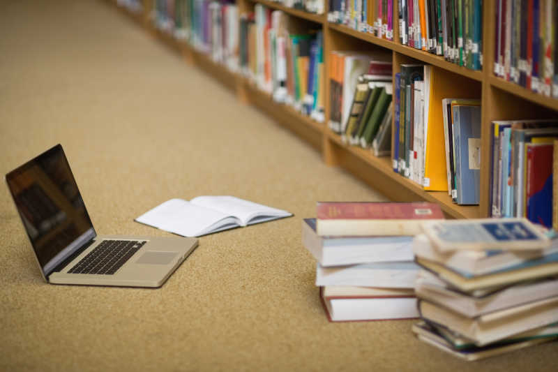 图书馆地板上的书和笔记本电脑