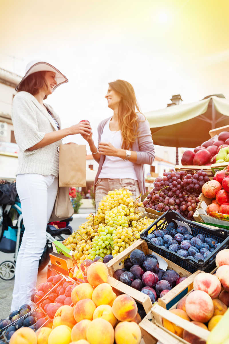 快乐的女人在蔬菜市场选择水果