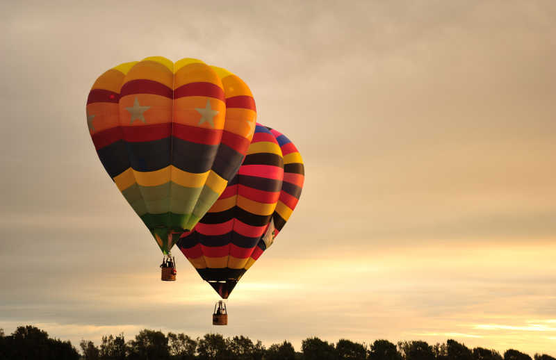 日出-日落背景下飞行的彩色热气球