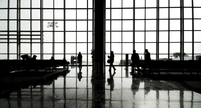 在有落地窗的机场候车室等待的人群剪影