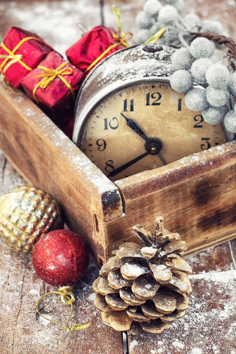 以圣诞装饰和松果为背景的木制盒子里的过时手表
