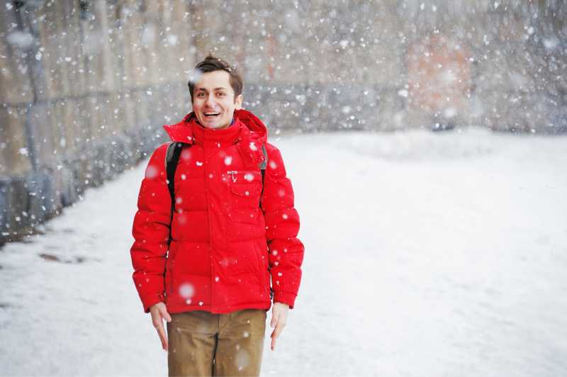 穿着冬天衣服的年轻英俊男子喜欢下雪