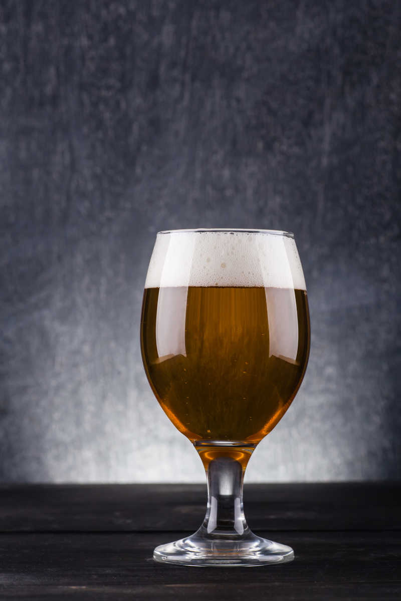 深色背景下的玻璃杯装满淡色啤酒