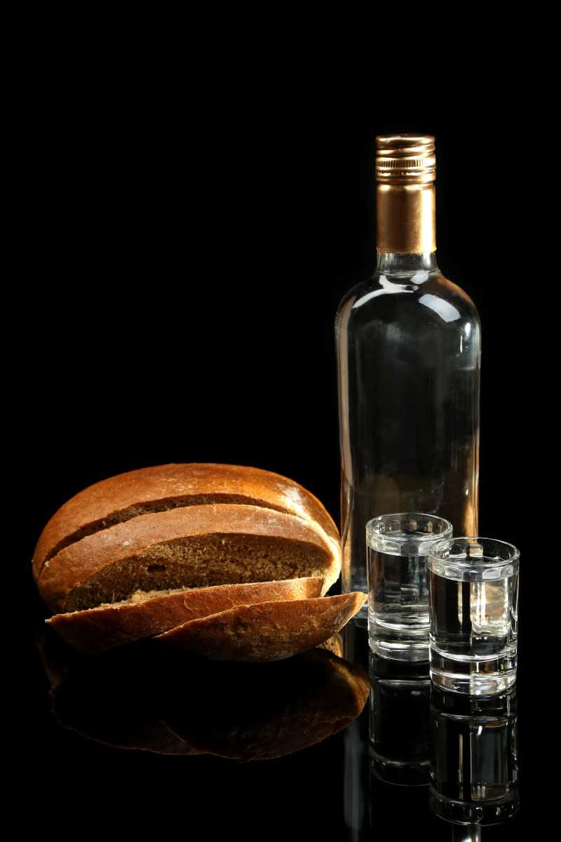 伏特加酒和新鲜面包在黑色的背景下