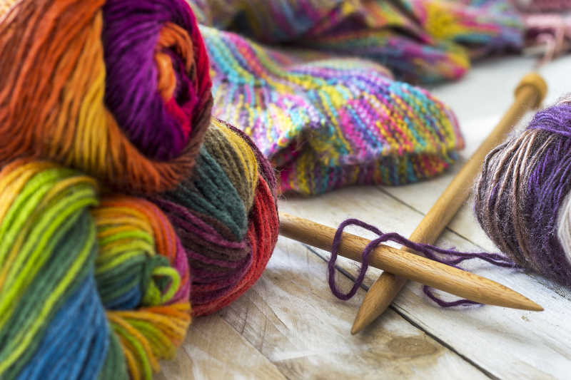 织针和木制背景毛衣羊毛彩色丝