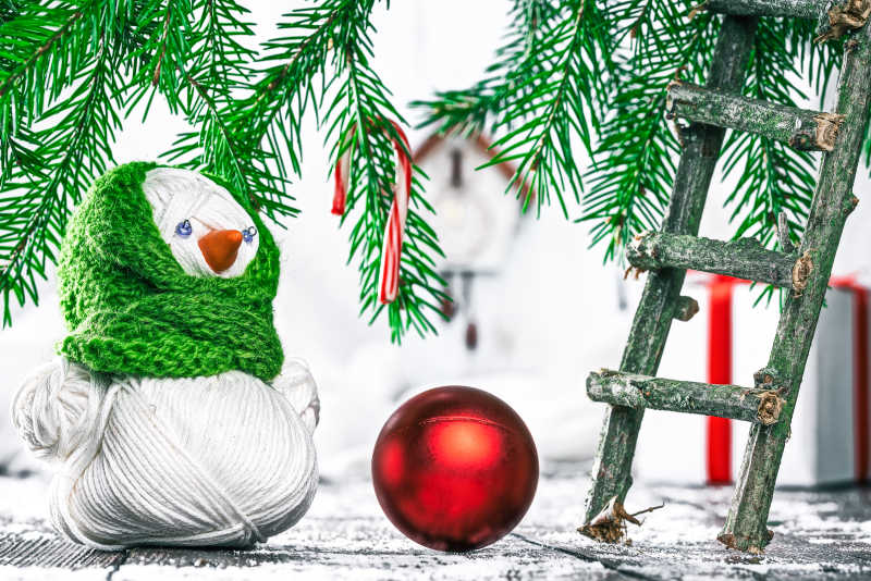 圣诞树下放着手工编织的雪人和红色圣诞球