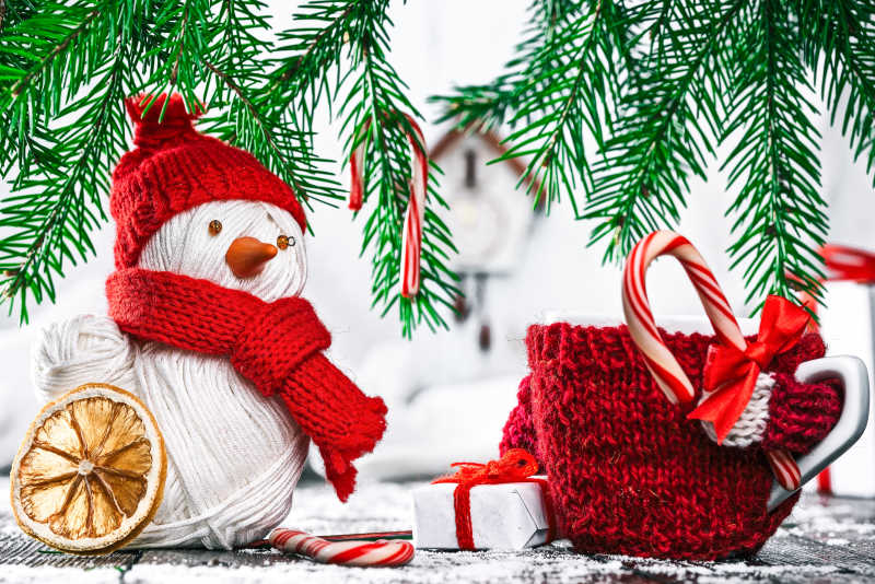 圣诞树下放着的手工纱线雪人和糖果杯