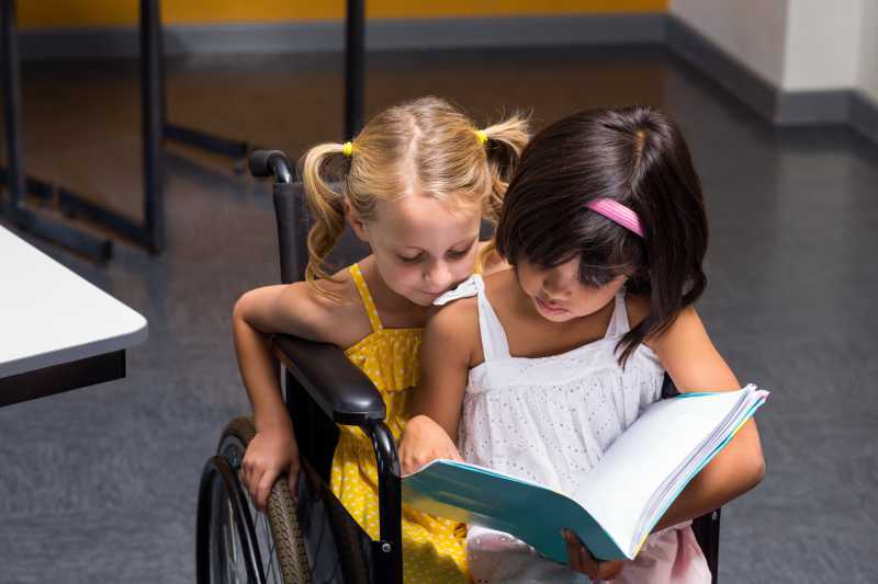 坐在轮椅上看书的两个女孩