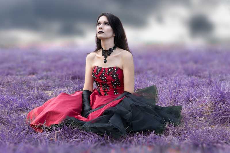 穿着红色连衣裙坐在紫色草地上的女人