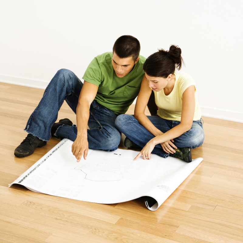 年轻夫妇坐在地板上看着房子计划