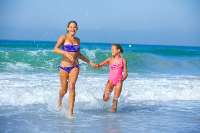 快乐的两个小女孩在海水里跑步