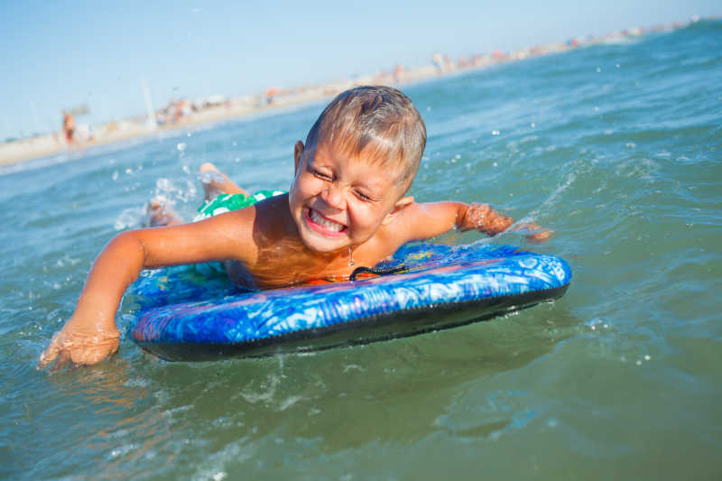 在海水中玩冲浪板的小男孩