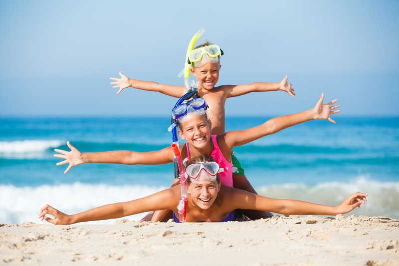 夏日海滩上三个带着潜水镜的快乐的孩子