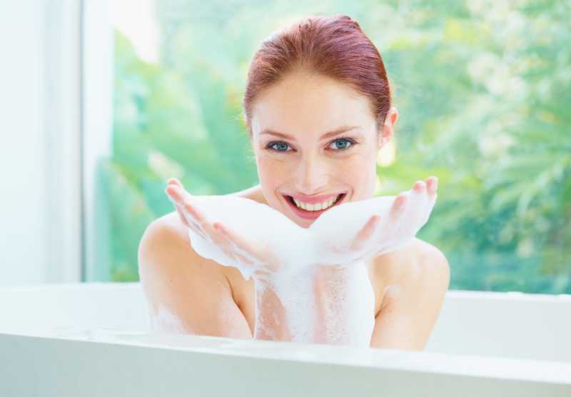 在浴缸里玩泡沫的快乐少妇