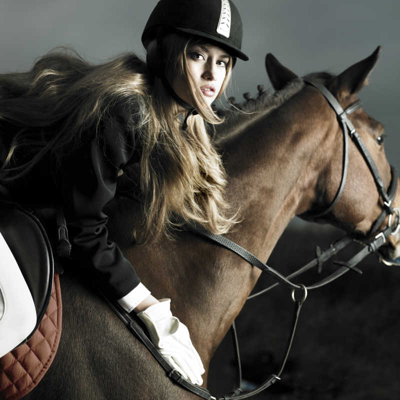 穿着黑色外套骑着棕色马的优雅女人