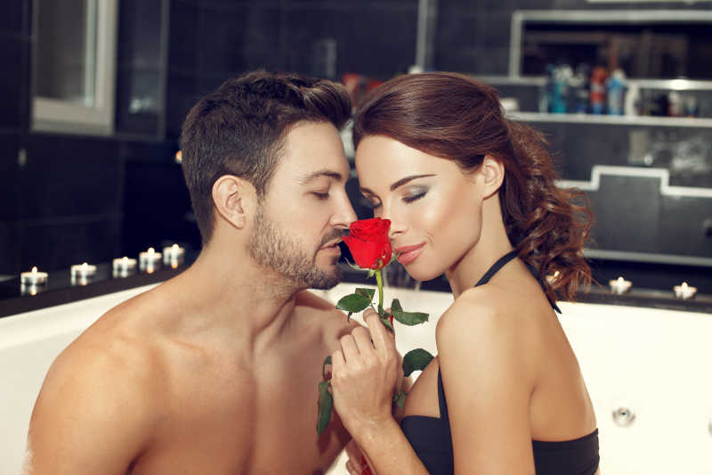年轻情侣在浴缸里闻着玫瑰的香气